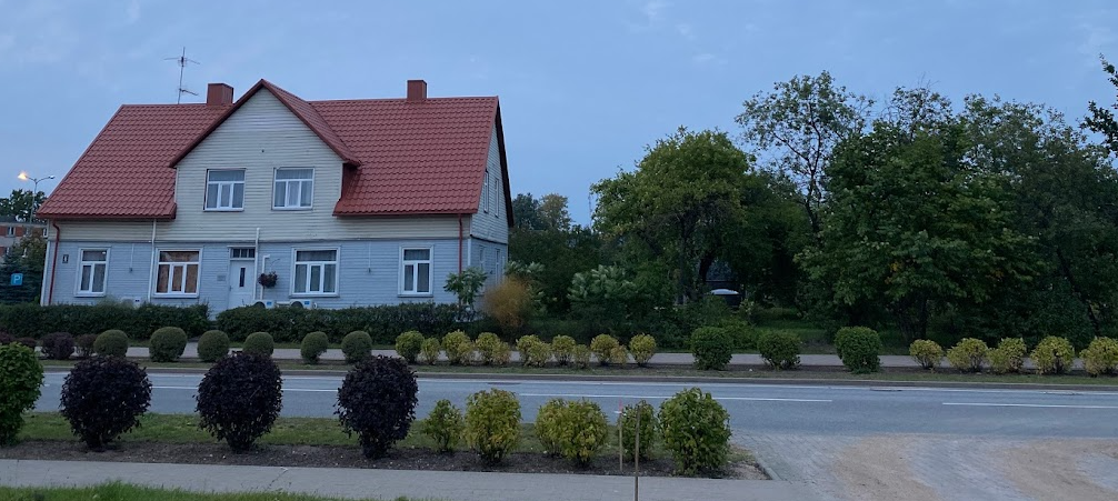 Skrunda Apartments trähus med rött tak och trädgård